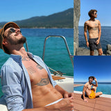 Man with tattoos lounges shirtless on yacht in blue sea, wearing orange hat and sunglasses.