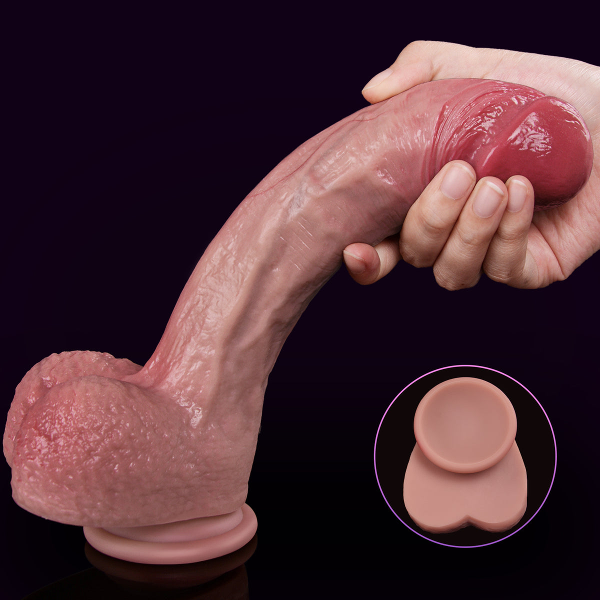 A hand holds a flesh-colored dildo with a red glans against a black background.
