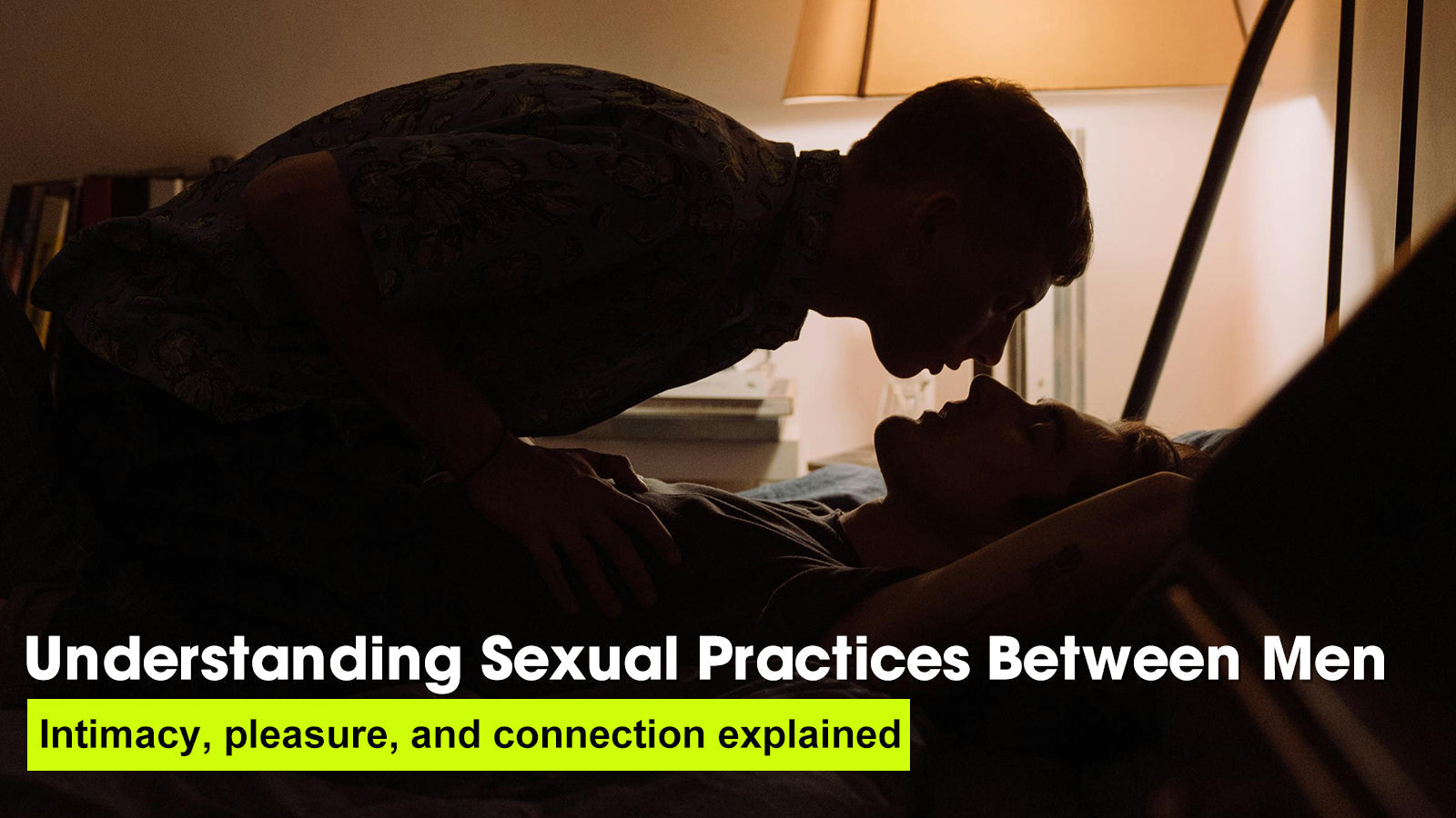 Two men share an intimate moment in a dimly lit room, focusing on connection and sexual health education
