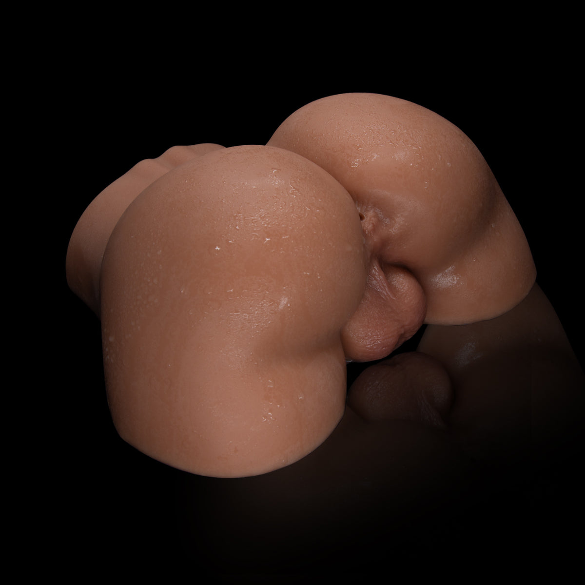 A baby lies curled up on a black reflective surface.